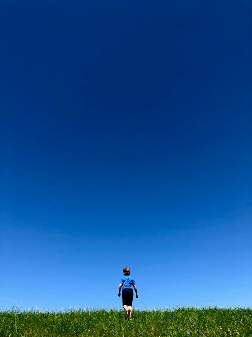 man in blue t-shirt and black shorts walking in green grass field