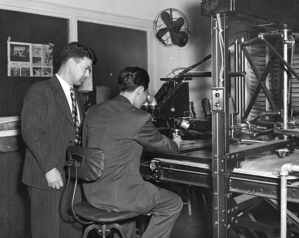 grayscale photo of two men using microscope