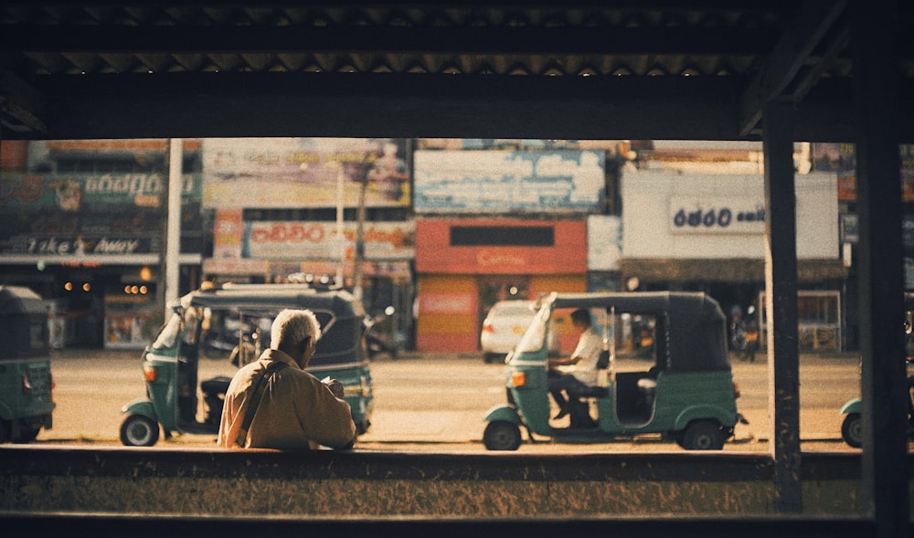 person sitting in a bench near cars during daytime