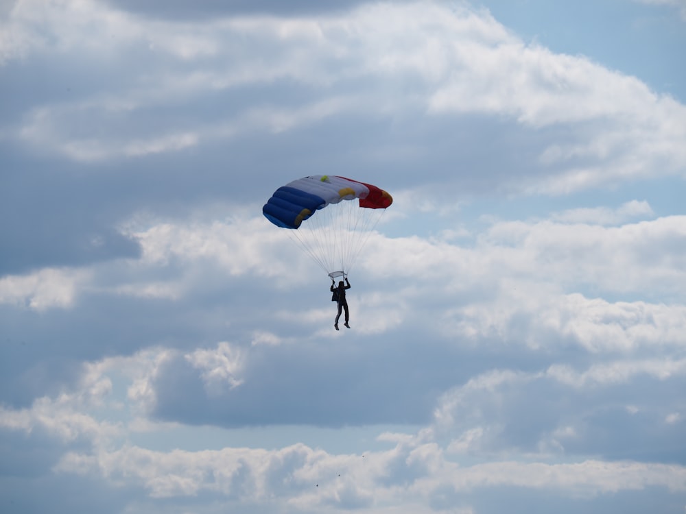 person with a blue, white and red parachute
