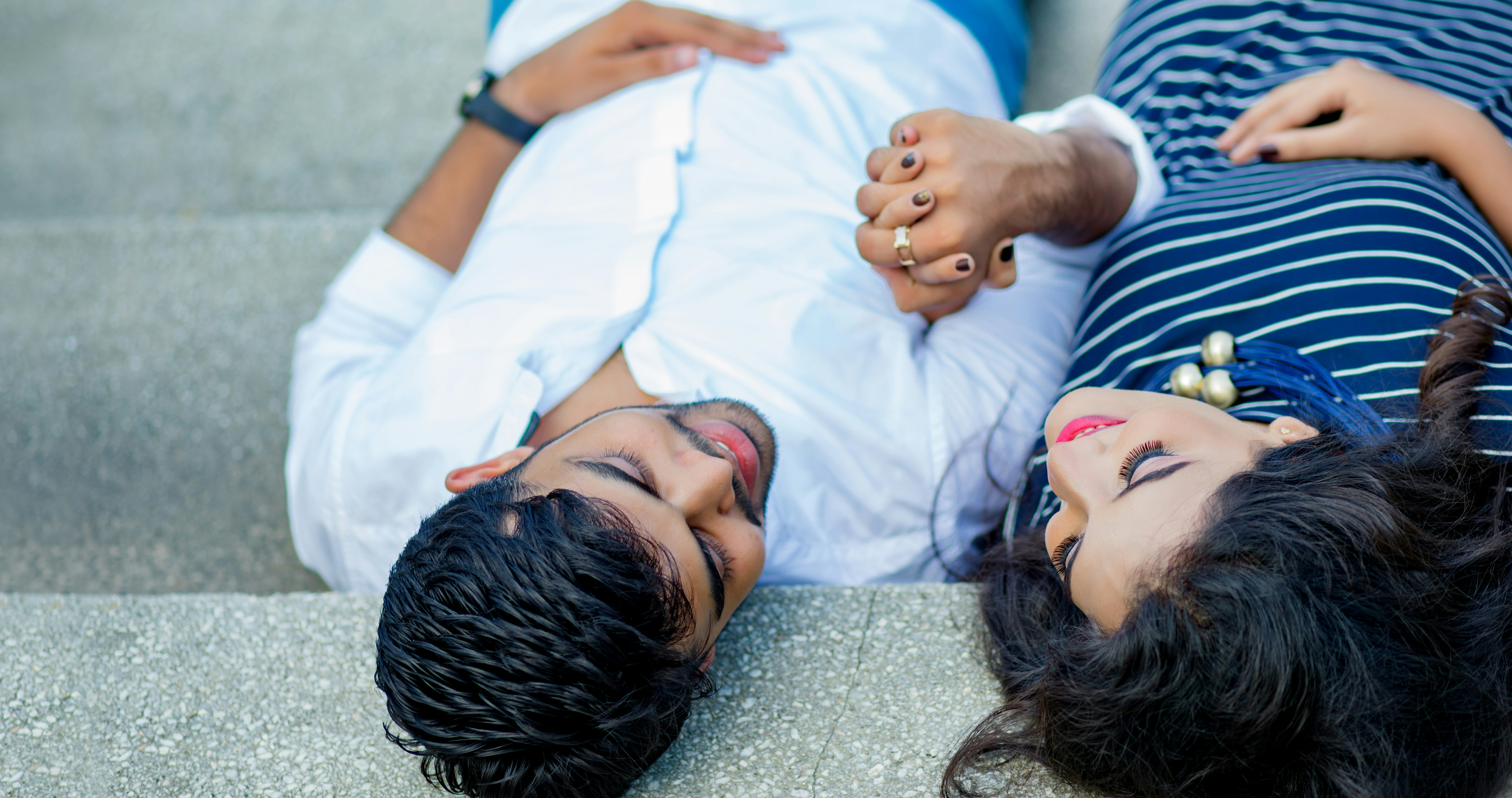 A woman and her partner sitting on a couch, holding hands, with a soft, understanding expression, representing calm communication during a sensitive cycle phase.