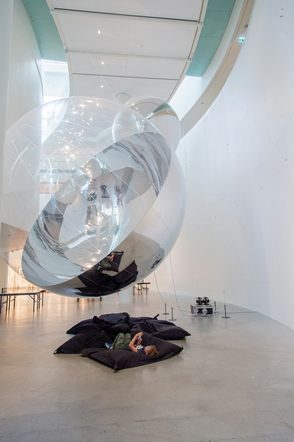 girl lying on floor under clear glass sphere statue