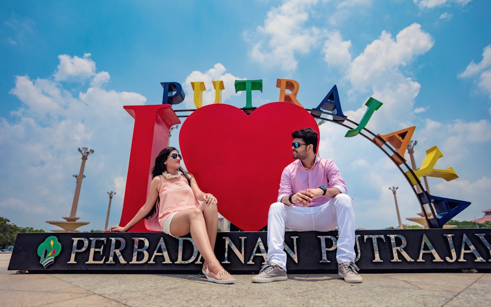 couple sits on signage under cloudy day