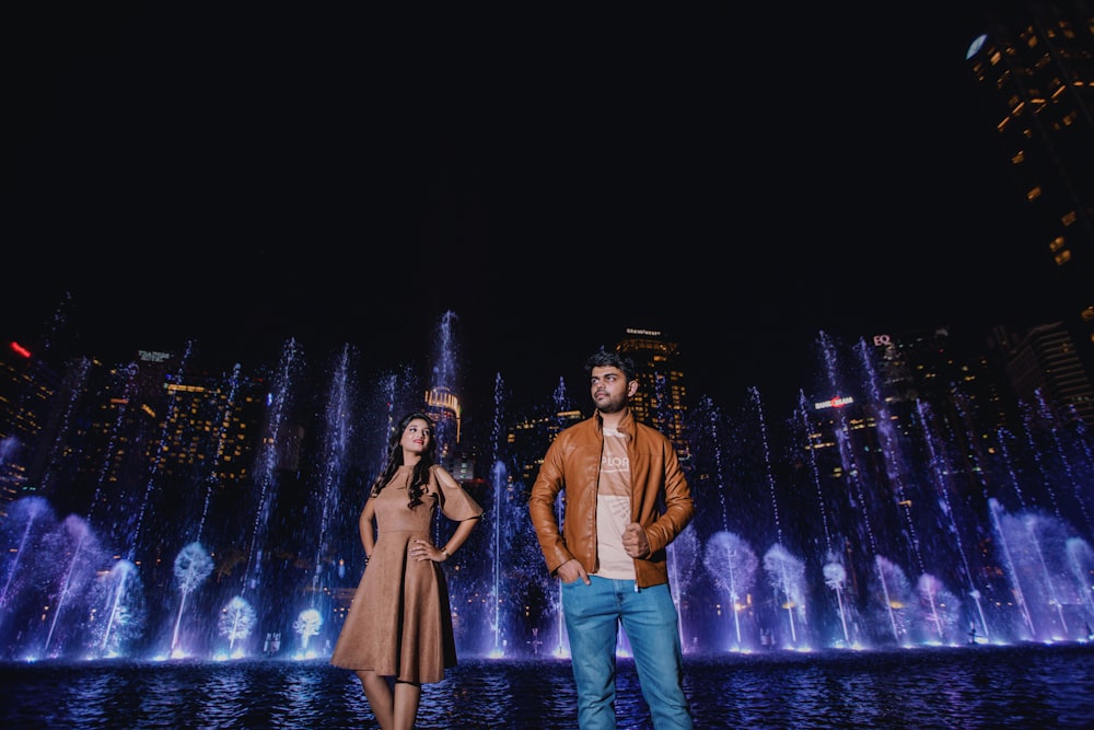 man and woman standing in front of fountain in park