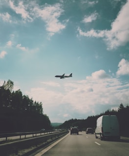 A truck transporting vehicles on a highway under a clear sky.