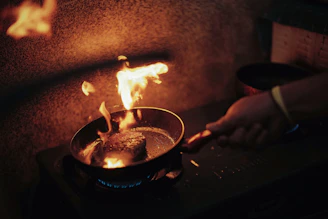 Close-up of a chef’s hand holding a digital thermometer over sizzling food.