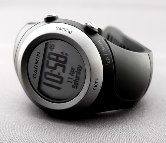 A close-up of a modern stopwatch displaying lap times against a blurred background of a fitness setting.