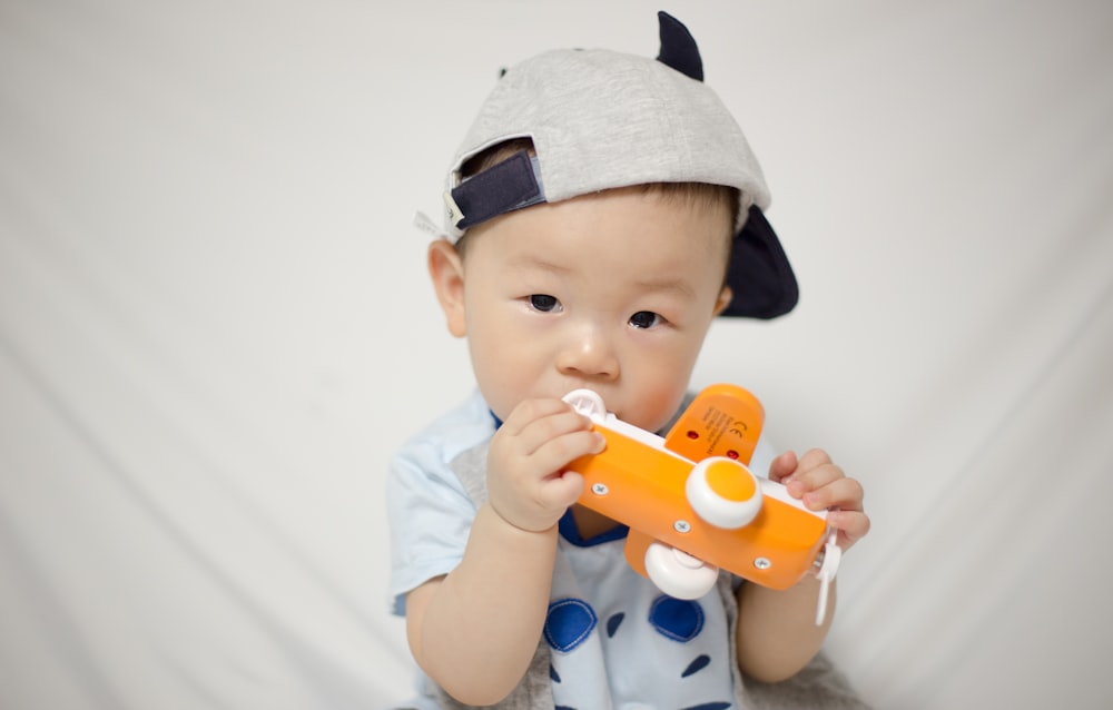 toddler holding white and orange plane toy