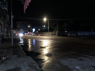 A calm, empty nighttime street reflecting city lights, ready for a private ride.