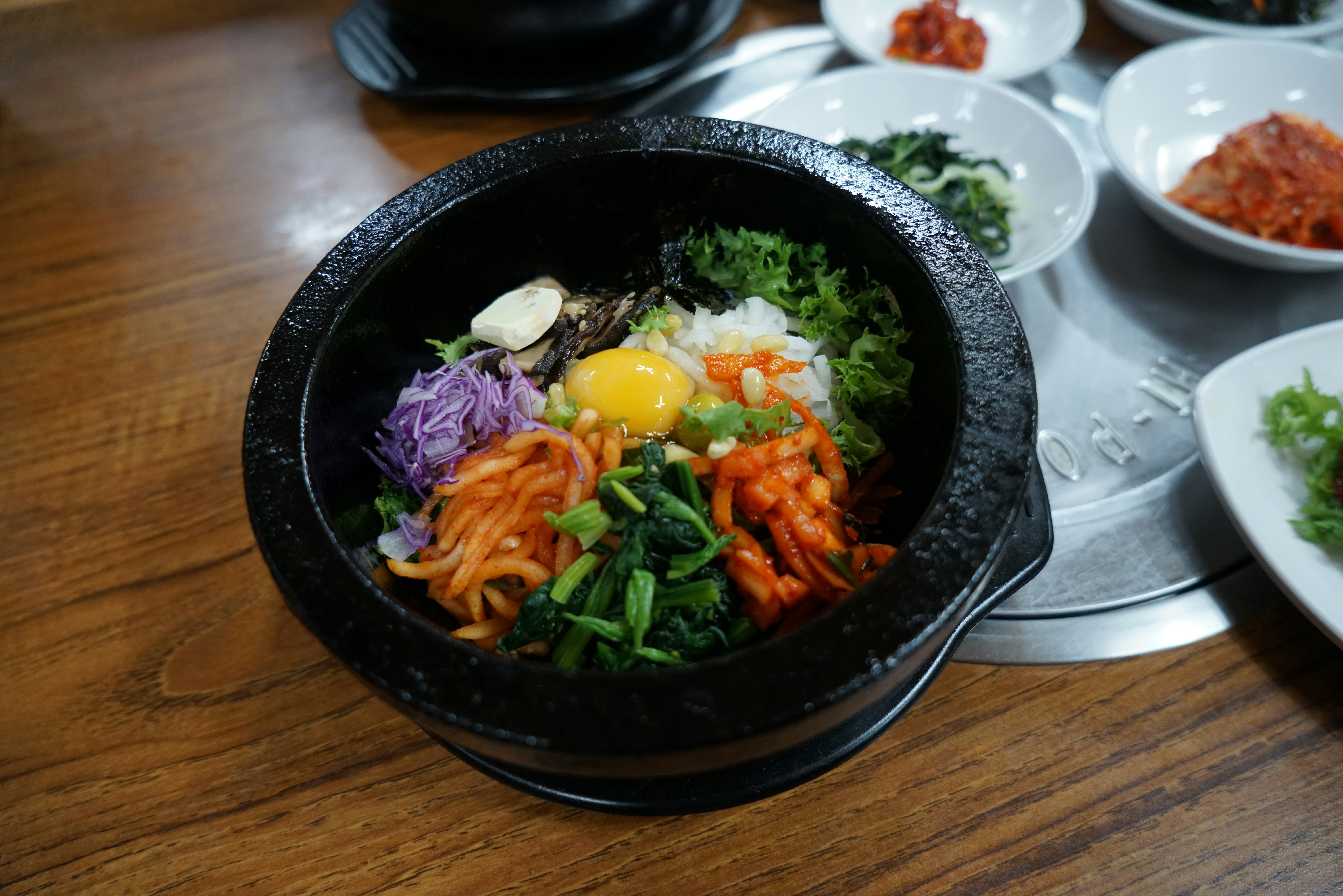 Colorful Korean bibimbap bowl with vegetables and gochujang on dark slate, low-key ambient lighting