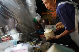 Elderly person preparing a healthy smoothie with fresh fruits and supplements.