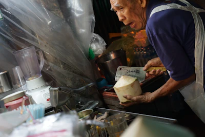 Elderly person preparing a healthy smoothie with fresh fruits and supplements.