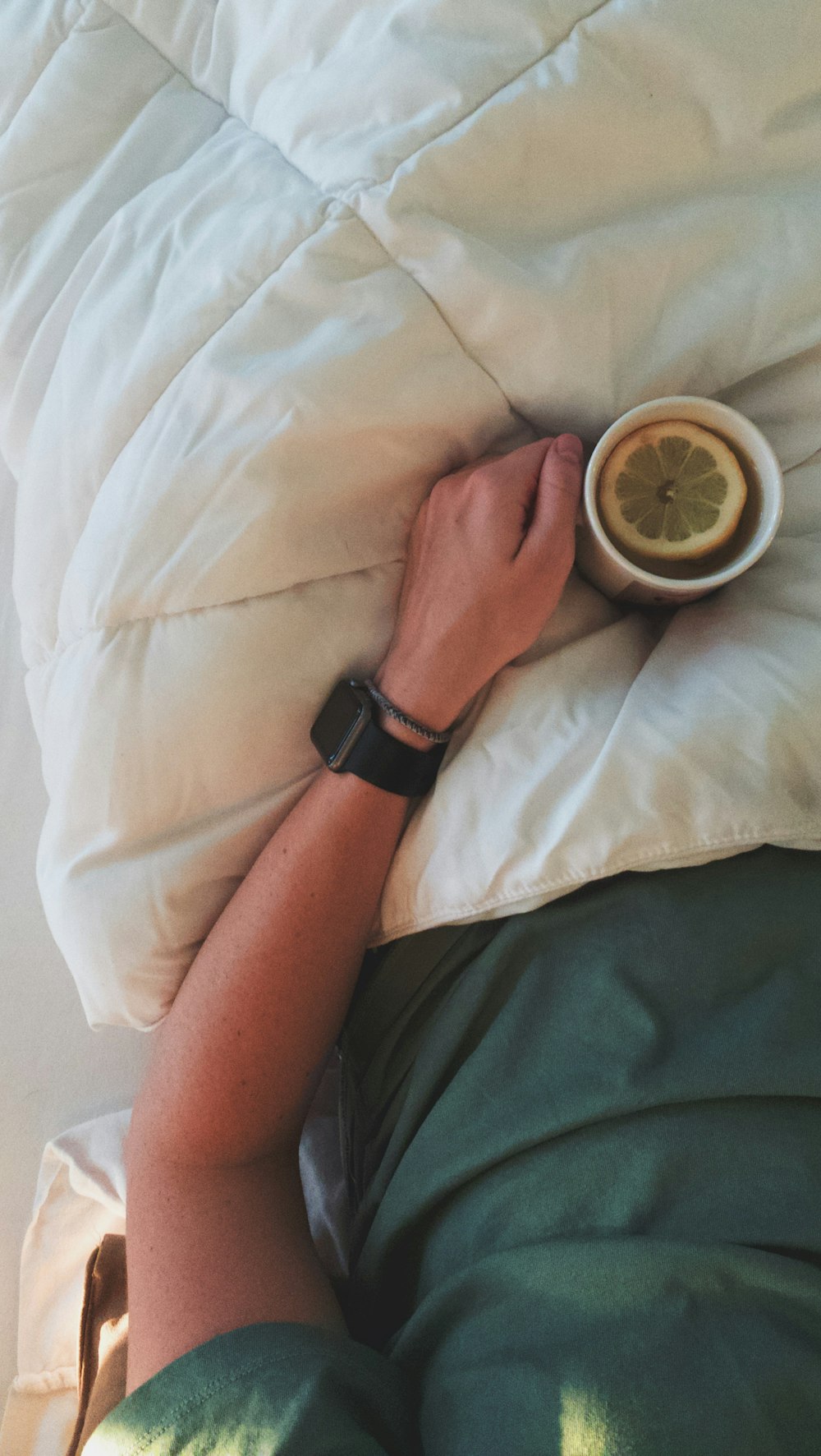 man lying on bed holding mug