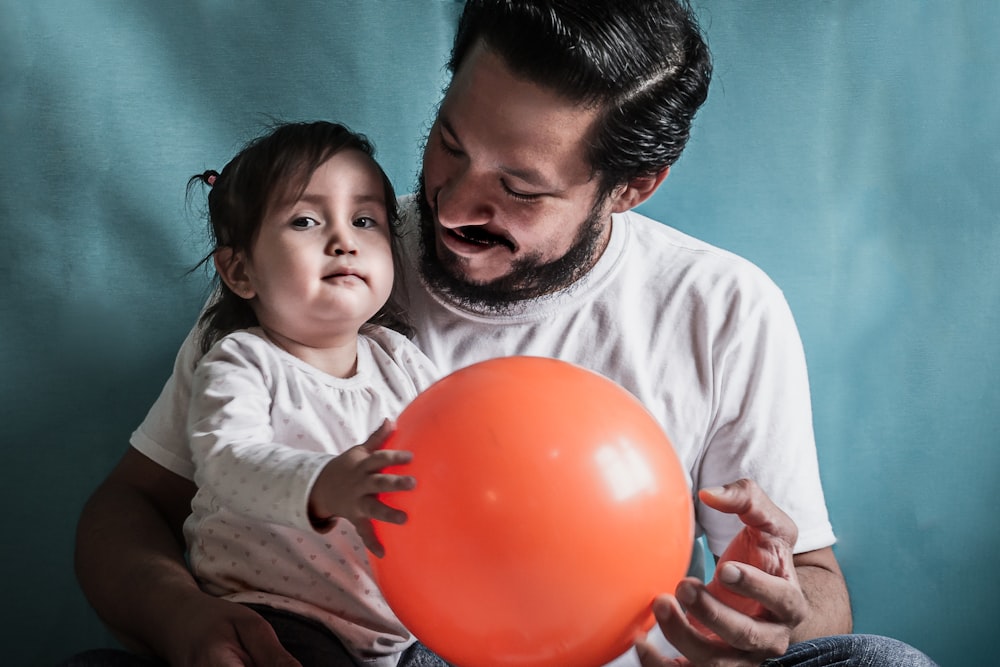 man and baby holding red balloon