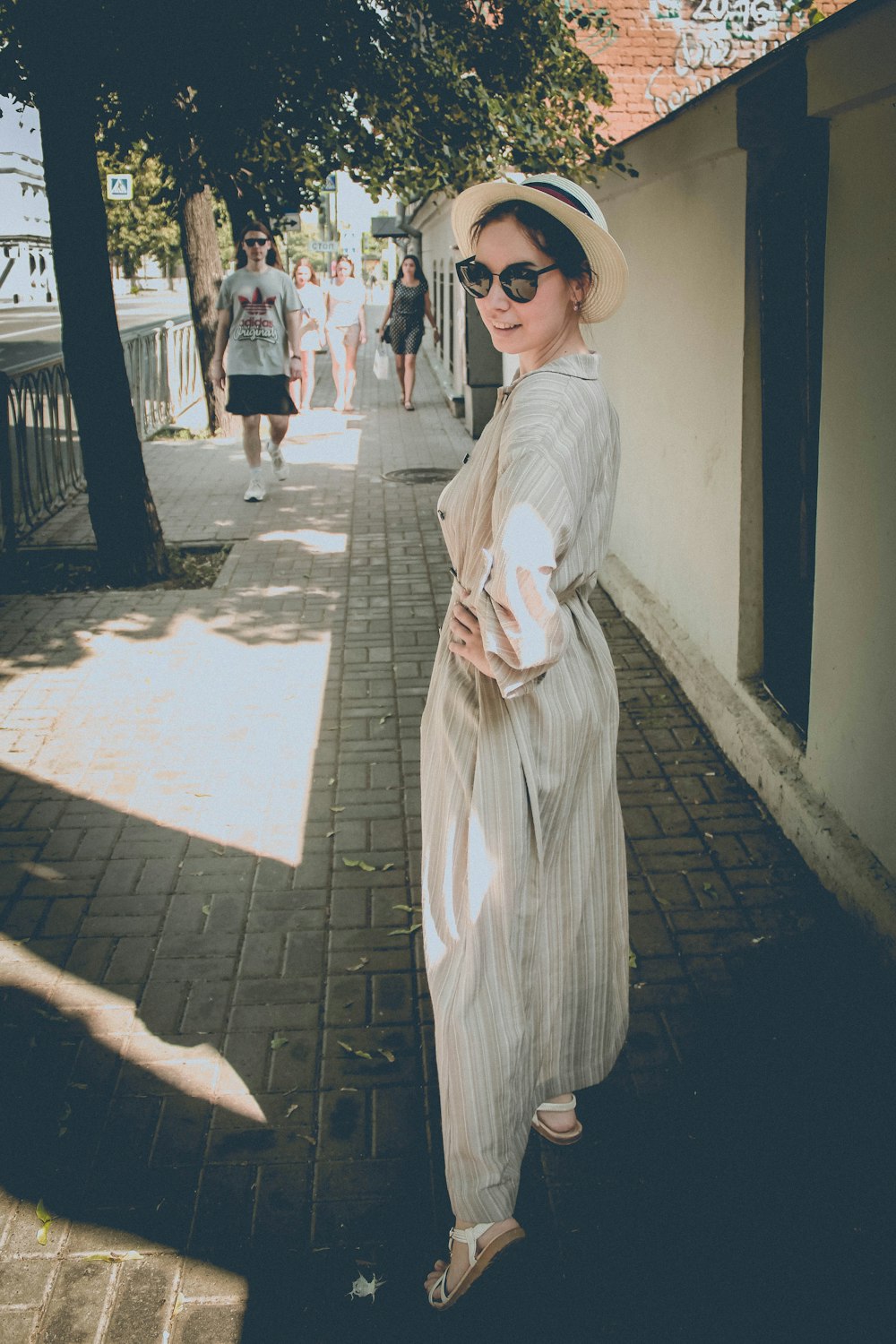 donna in cappello bianco e vestito in piedi vicino al muro