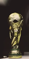 A golden trophy featuring a globe supported by two human figures, intricately designed with a shining metallic surface.
