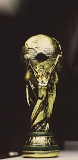 A golden trophy featuring a globe supported by two human figures, intricately designed with a shining metallic surface.