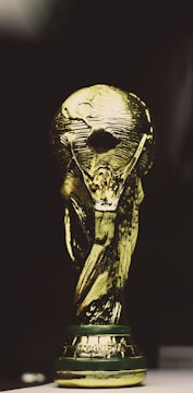 A golden trophy featuring a globe supported by two human figures, intricately designed with a shining metallic surface.