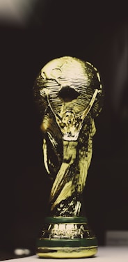 A golden trophy featuring a globe supported by two human figures, intricately designed with a shining metallic surface.