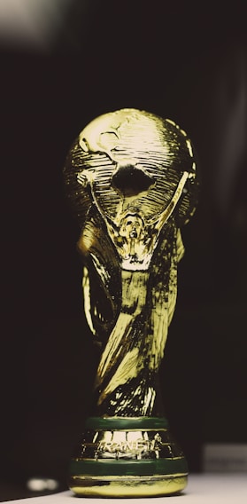 A golden trophy featuring a globe supported by two human figures, intricately designed with a shining metallic surface.
