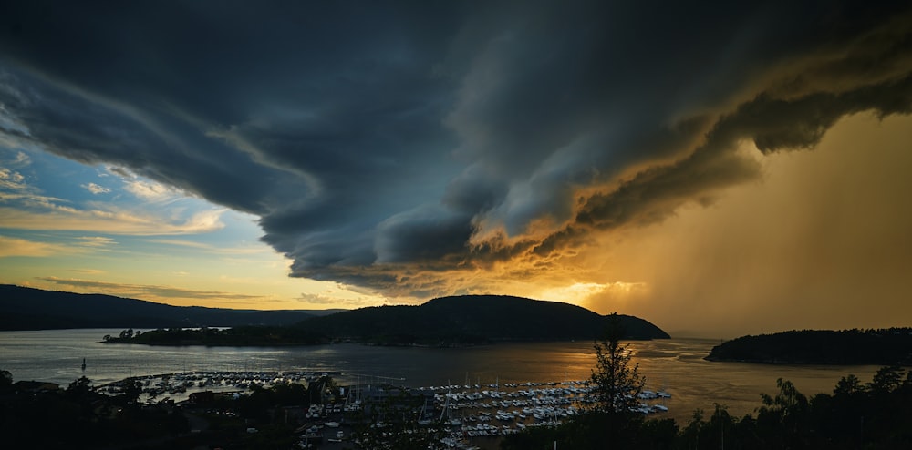 a large storm cloud looms over a city at sunset