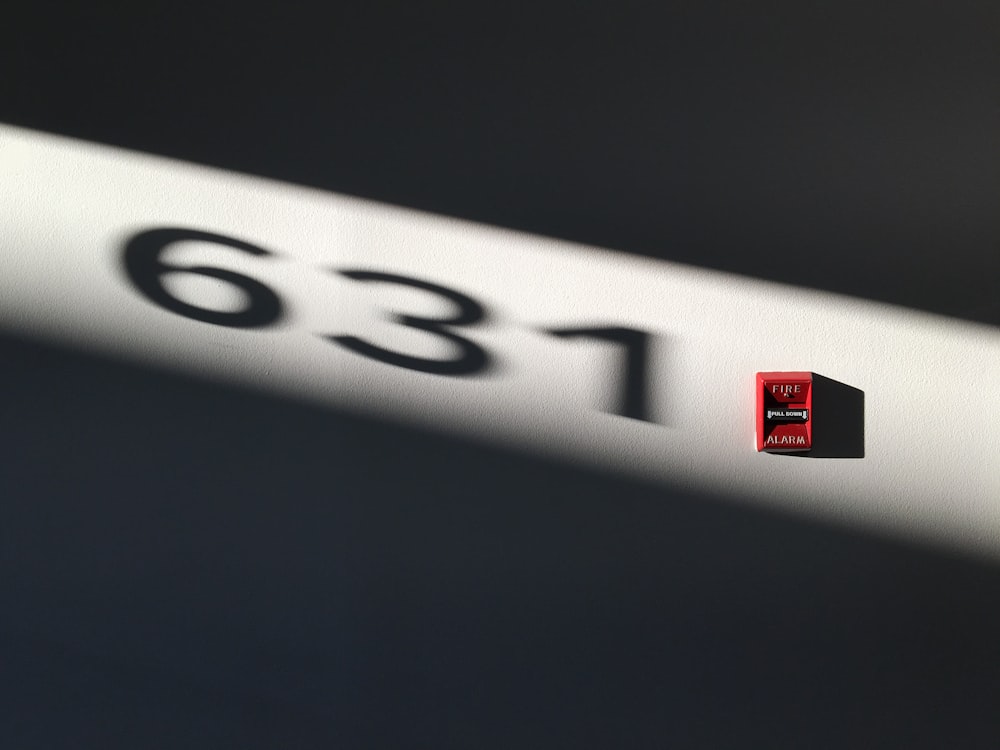 a close up of a red and black logo on a white wall