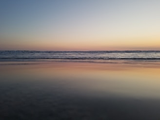 A tranquil beach scene with soft waves and a sunset.