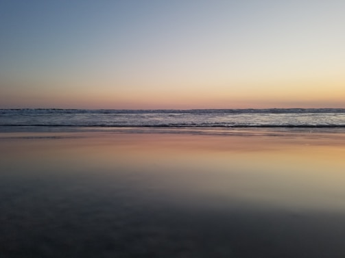 A tranquil beach scene with soft waves and a sunset.