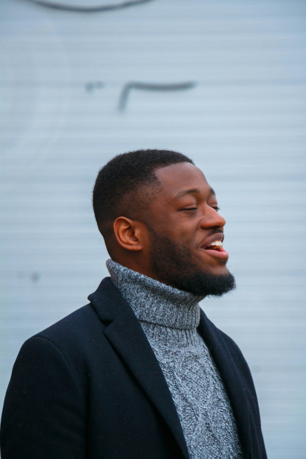 man wearing sweater standing near building