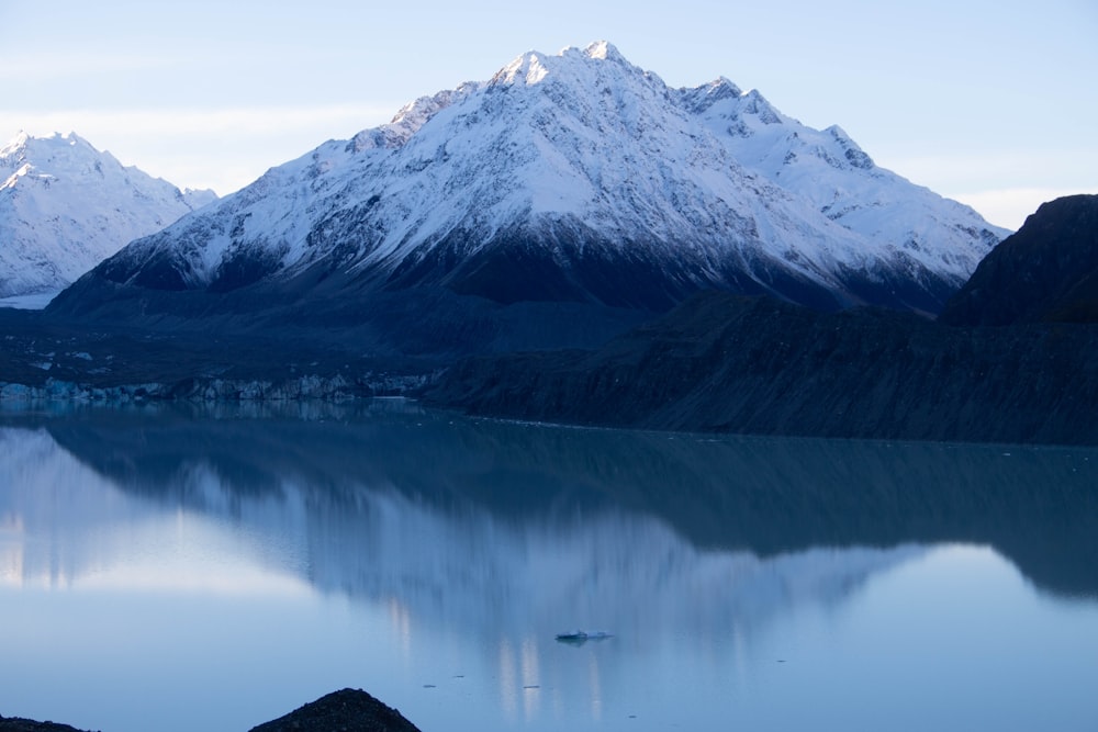 calm lake in between snow covered mountain during daytime