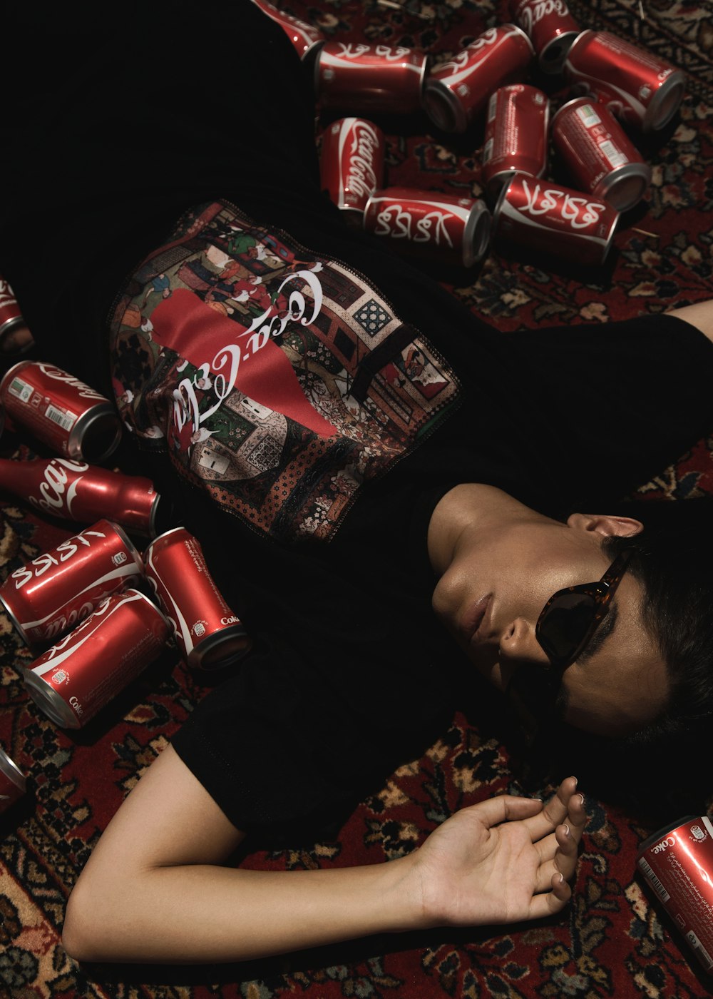 person lying on floor near Coca-Cola cans