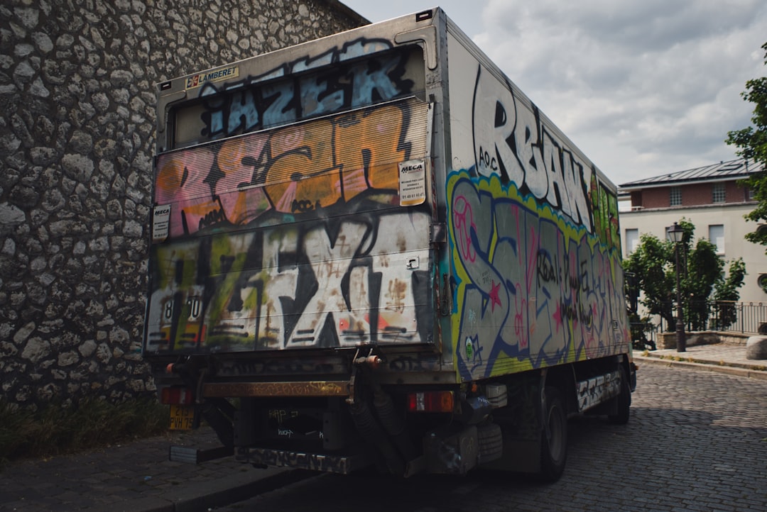 white and green truck near grey concrete wall