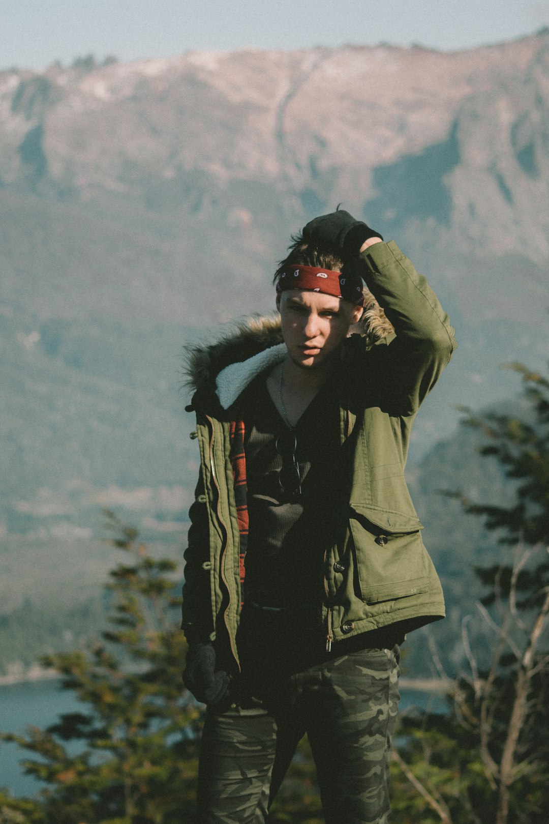 man in green parka jacket standing on hill during daytime