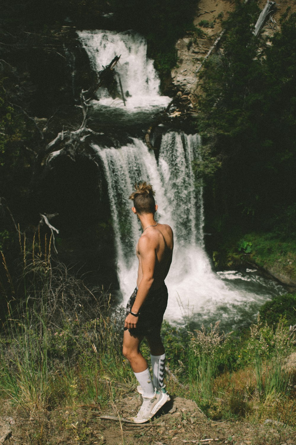 man standing near waterfall