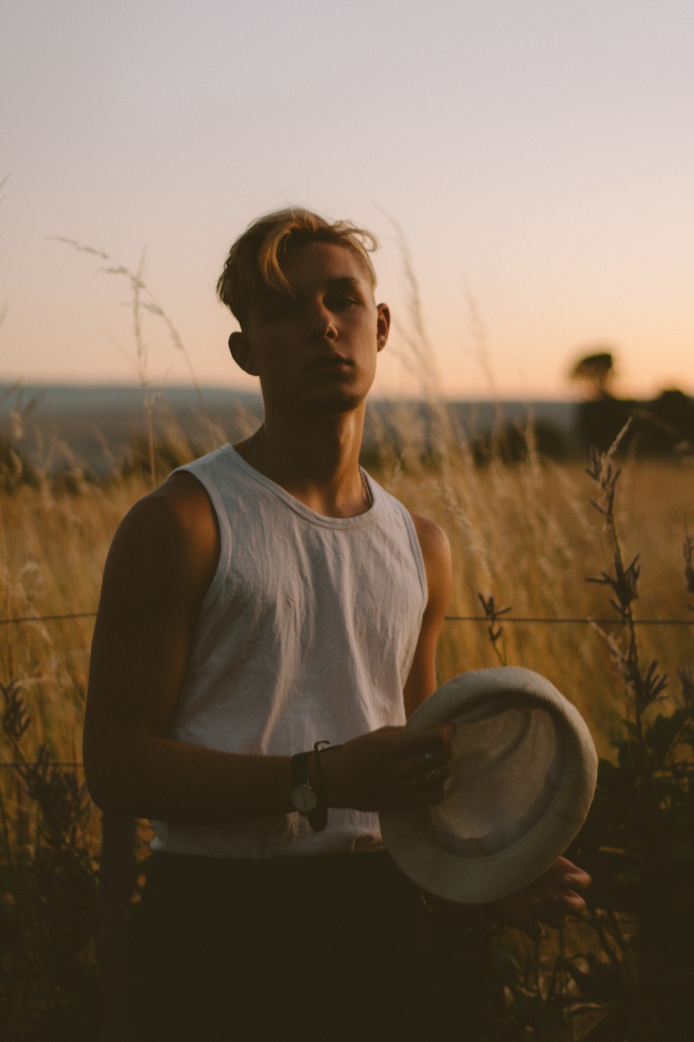 man in white tank top holding cap