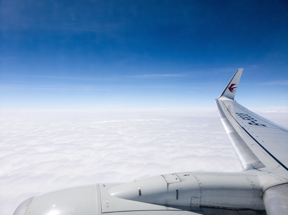 Foto aérea de avión volando por encima de las nubes bajo un cielo azul claro