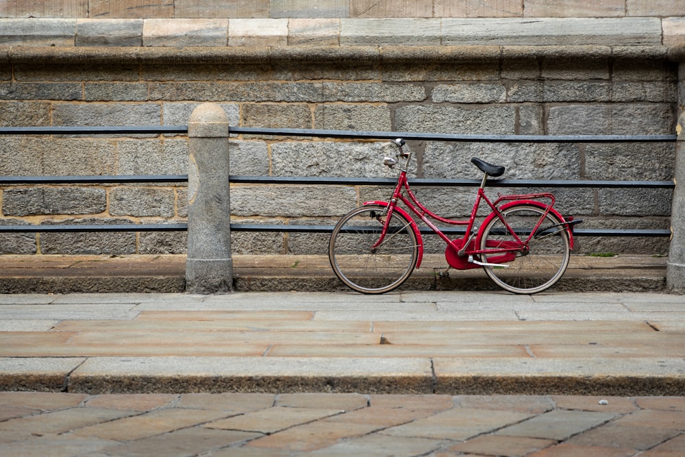red bicycle leaning on rail