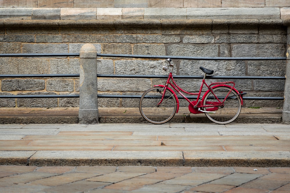 Bicicleta roja apoyada en el riel