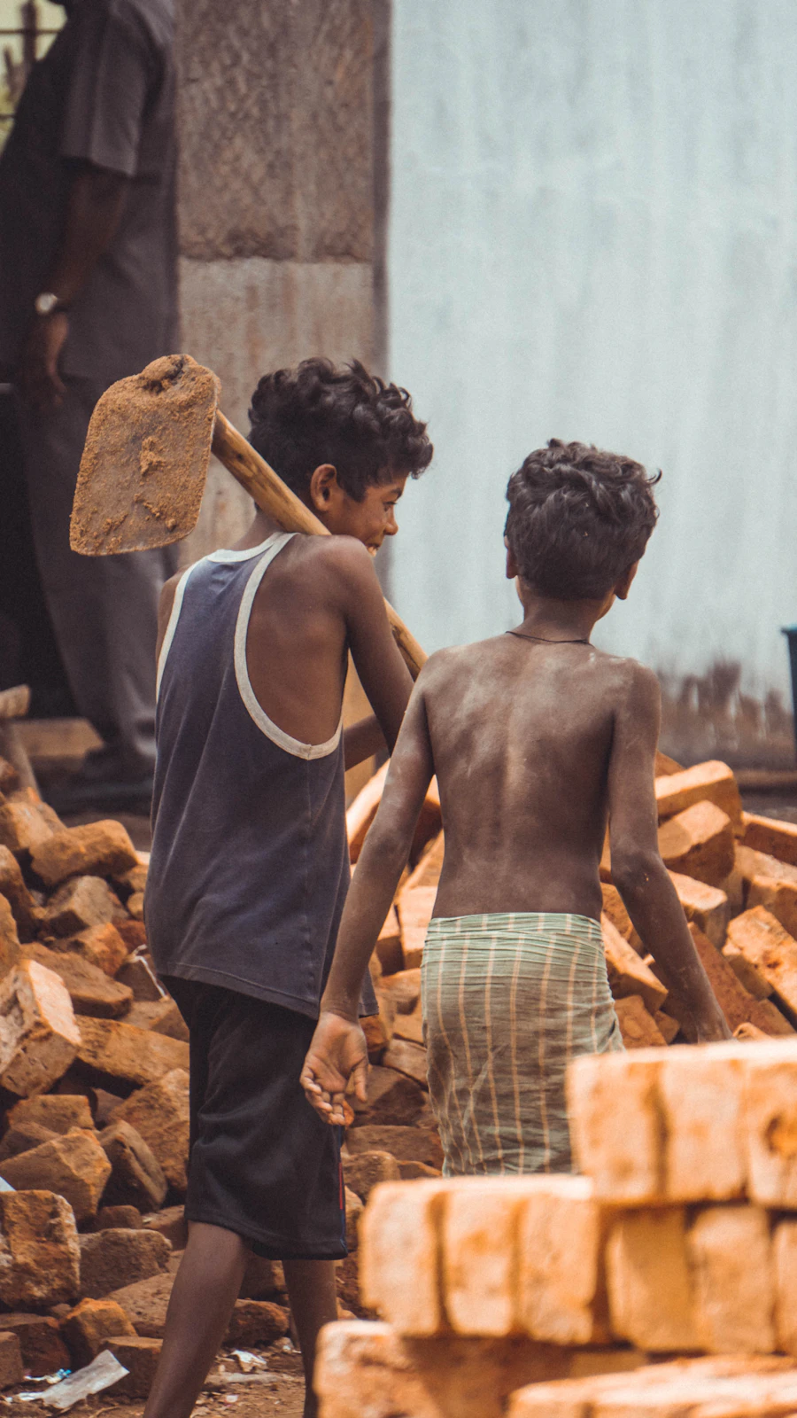 Two boys walking near pile of bricks — child labour