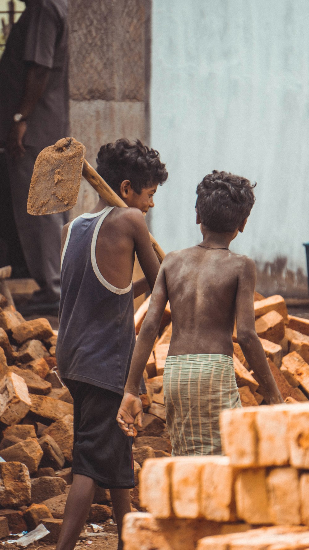 two boys walking near pile of bricks