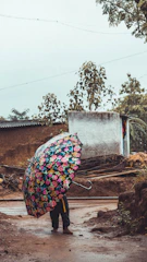 A wide, sturdy umbrella open under a summer drizzle with bright floral patterns.