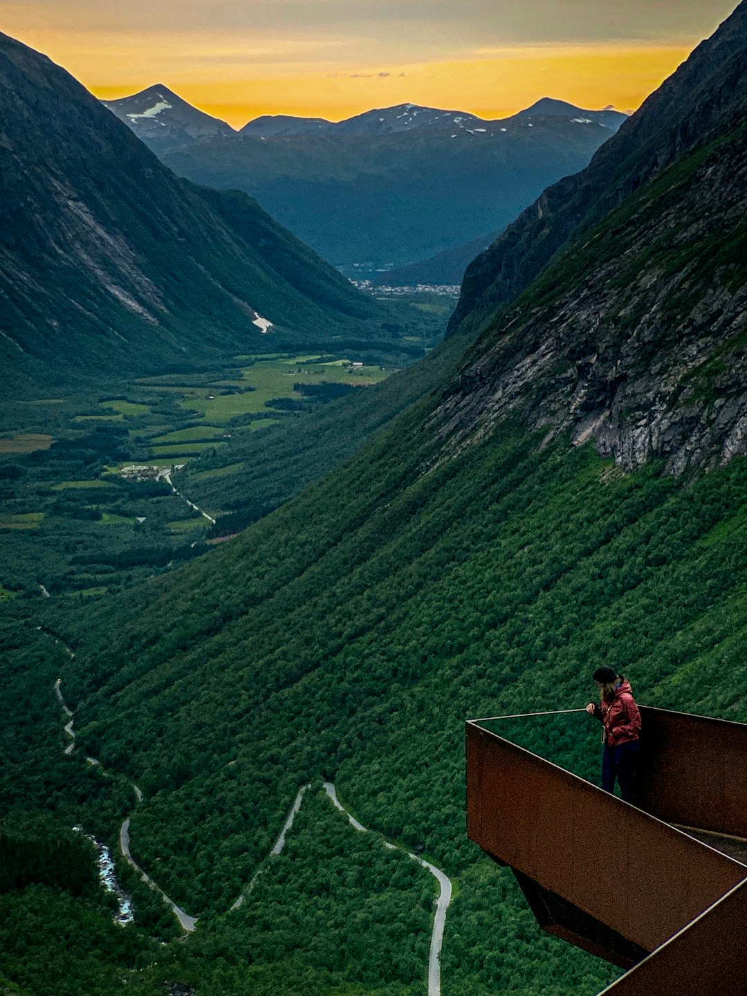 man standing on metal balcony near the mountains