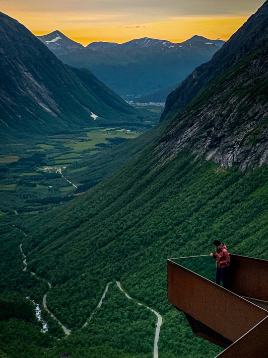 man standing on metal balcony near the mountains in Trollstigen Norway