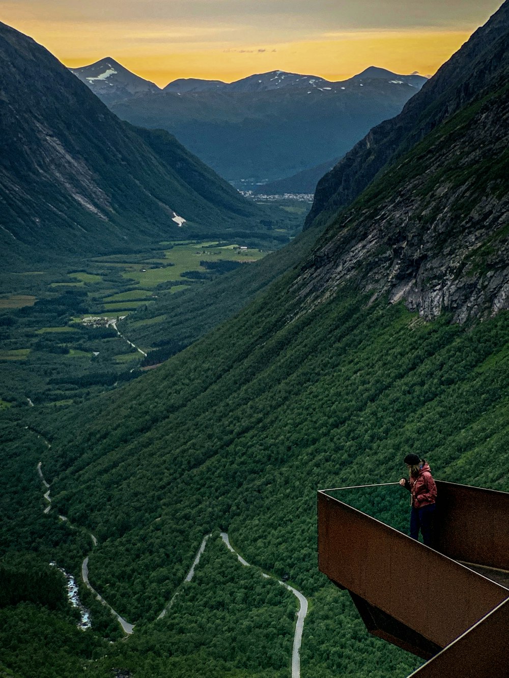 man standing on metal balcony near the mountains