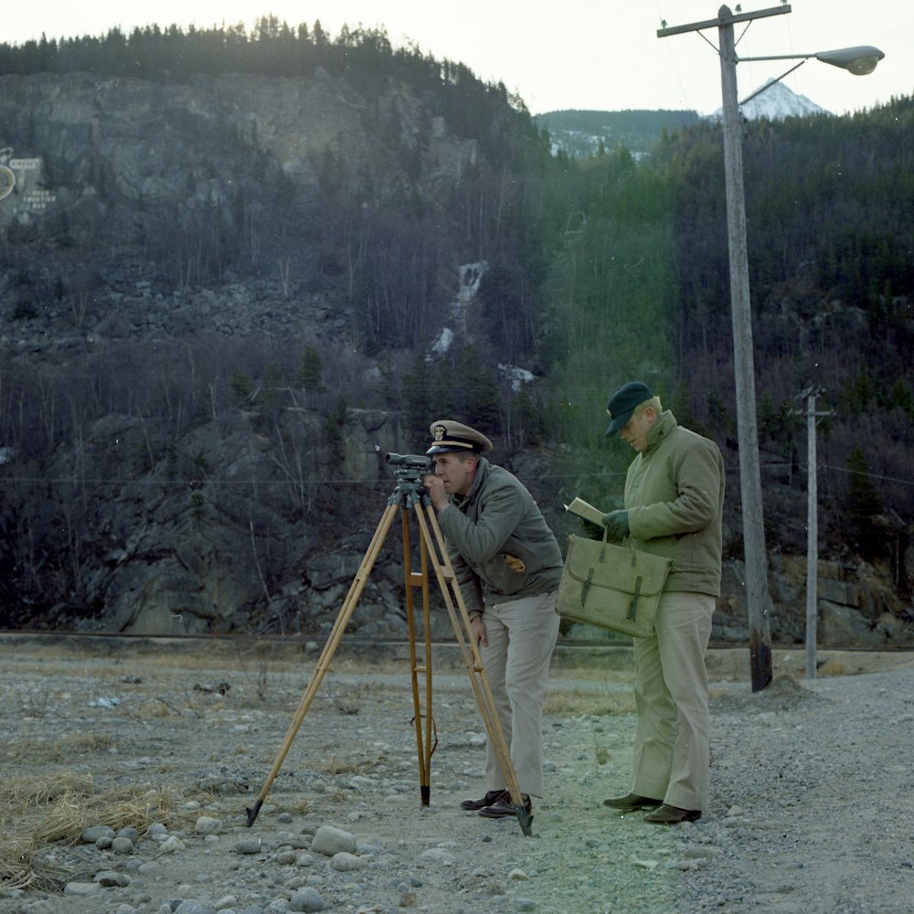 man measuring land and another man holding paper