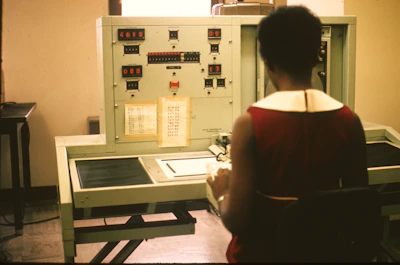 A young professional in 1980s attire studying technical manuals under warm office lighting.