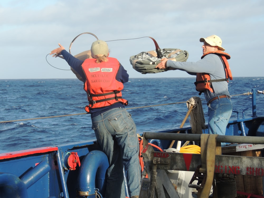 two men standing and throwing rope on sea