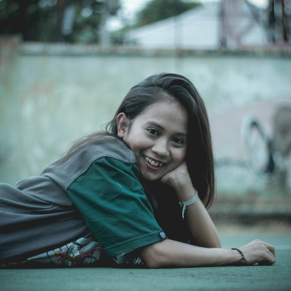 woman wearing grey and green top laying down on pavement