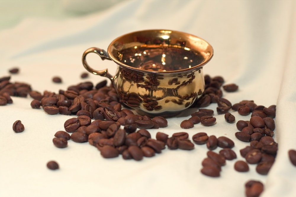 brass-colored teacup with coffee beans