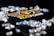 A collection of sparkling, clear gemstones surrounds a dark surface featuring the prominent logo and text 'Real Poker.' The logo design includes gold and white elements set against a black background.